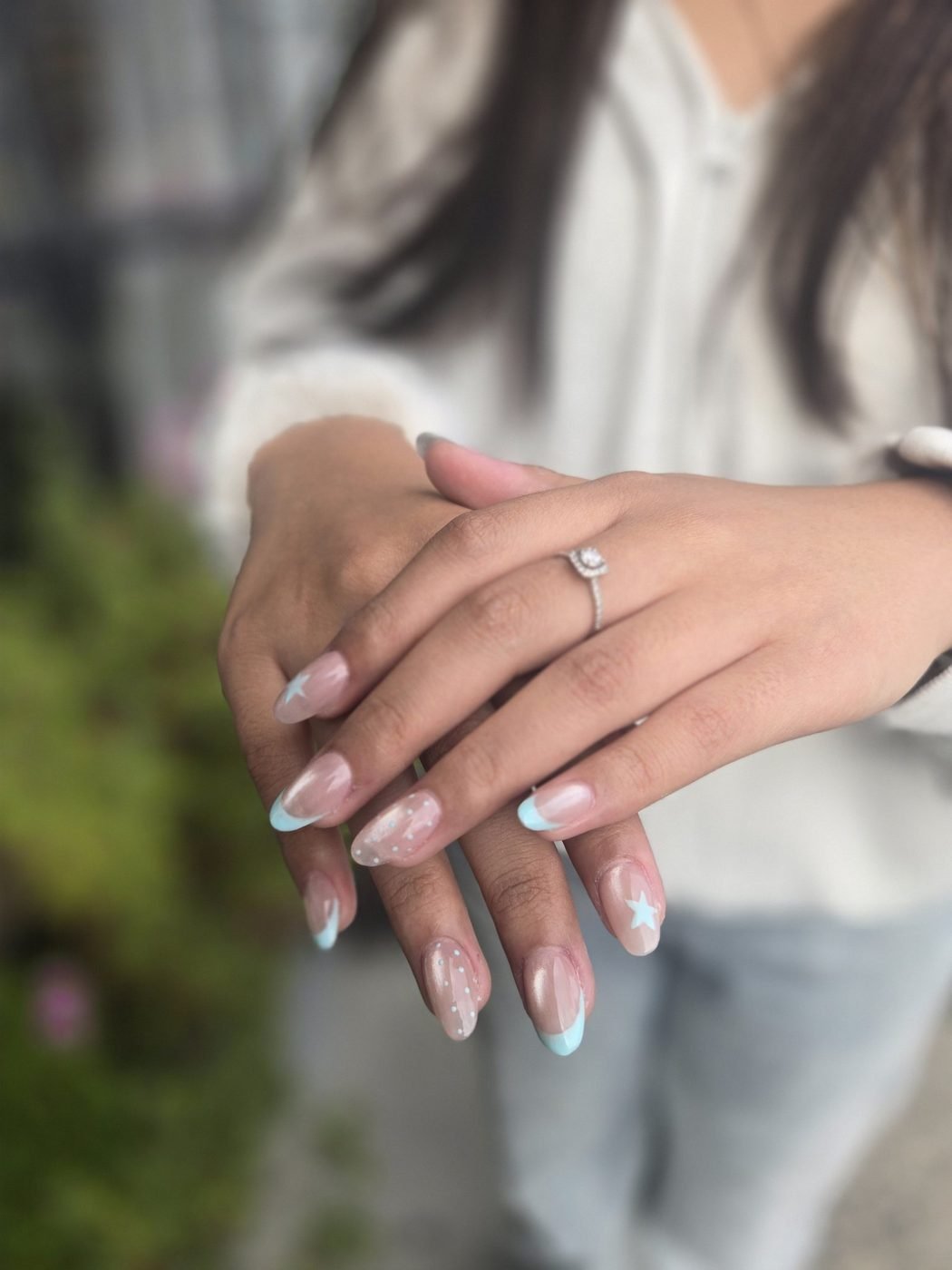 Soft nude almond nails with pale blue French tips and little star details